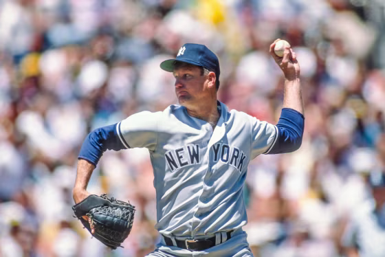 Tommy John throws a baseball on the field