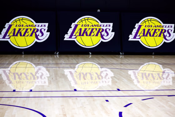 The Los Angeles Lakers logo, printed three times on the wall, appears on the basketball court with reflections on the floor