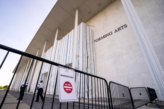 The John F. Kennedy Center for the Performing Arts exterior, tarp covers the front, and a gate can be seen blocking off entry, a sign is on the gate that reads "restricted area, and a Do Not Enter logo"
