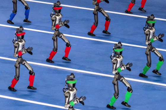 Humanoid robots walk in procession on a blue track