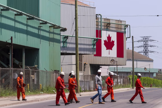 Workers leave an ArcelorMittal Dofasco's steel manufacturing building in Hamilton, Ontario, in 2025.