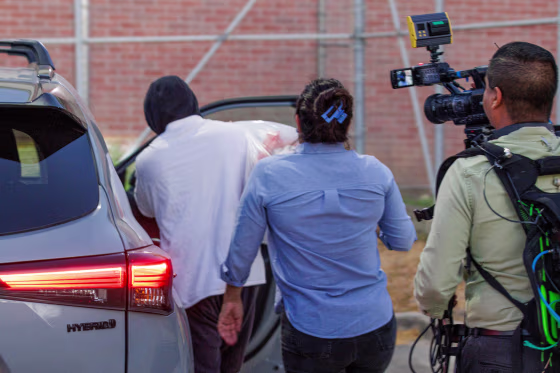 Immigration and Customs Enforcement officer Christian Castro gets into a car surrounded by news reporters.