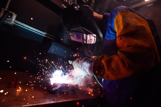 A person appears to be welding while wearing protective clothing.