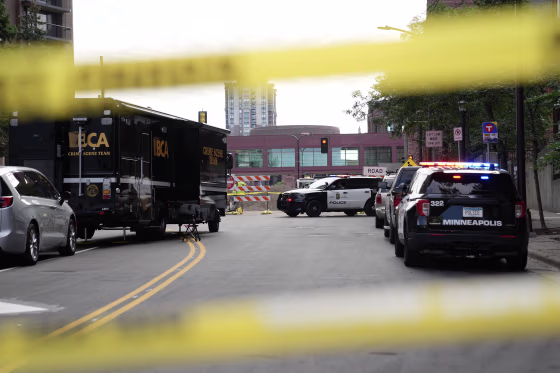 A crime scene investigation with law enforcement vehicles and yellow tape around the perimeter.