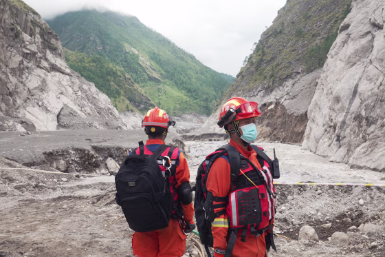 Image: Two rescuers in orange emergency services uniform.
