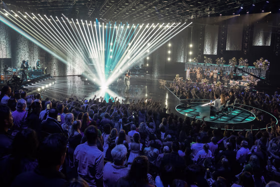 A wide view of the audience, judges, and a performer on stage during American Idol.