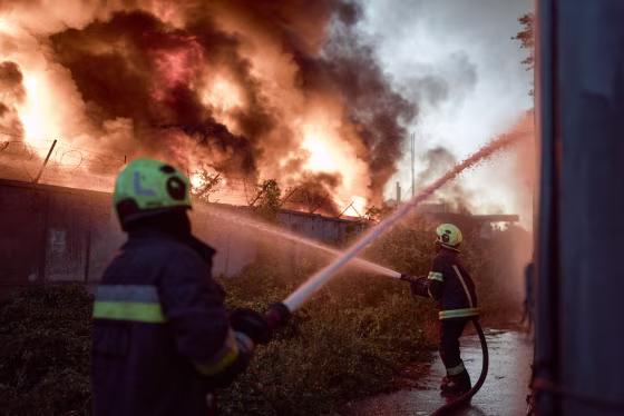 Members of emergency services work to contain a fire from the outside of the building