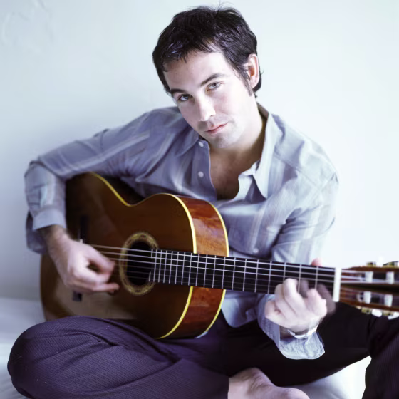 Duncan Sheik holding an acoustic guitar