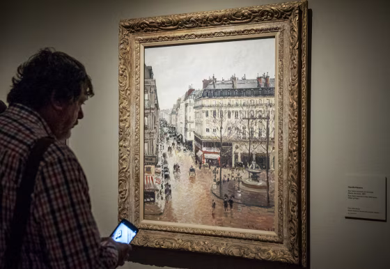 Museum goer looks at the painting 'Rue Saint-Honore por la tarde. Efecto de lluvia.'