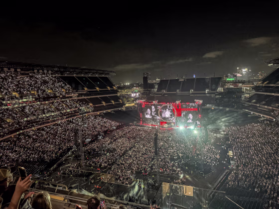 A wide shot of an outdoor stadium concert at night.