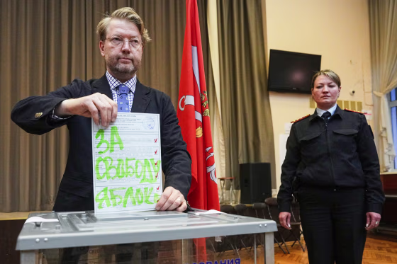 Nikolai Rybakov casts a ballot with a writing in Russian reading "For freedom"
