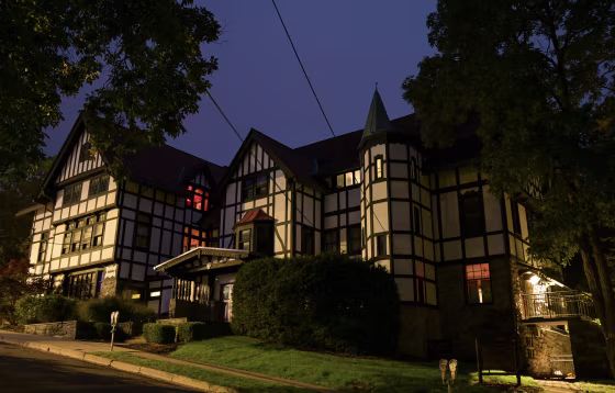 A white and black paneled fraternity house near Cornell University at night.