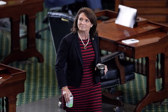 Angela Paxton in the Texas Senate Chamber, carrying two beverages.