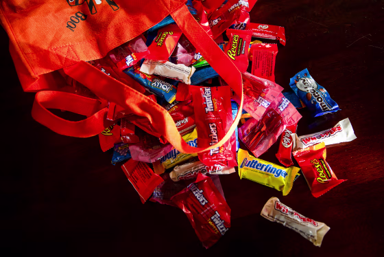 Halloween candy spilled from an orange bag onto a table