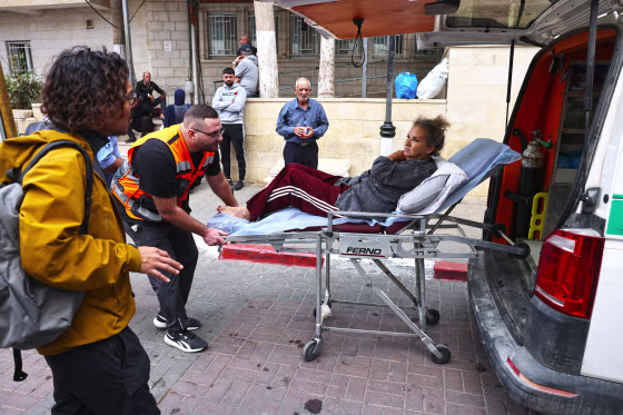 Image: Heidi Levine on a stretcher being wheeled into an ambulance.