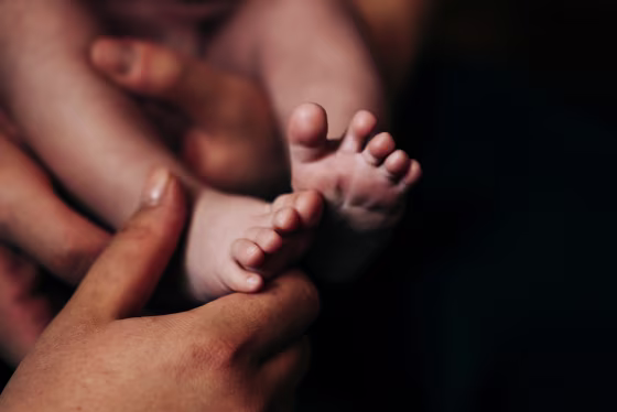 Close-Up of Tender Baby Feet Held by a Caring Mother Hand
