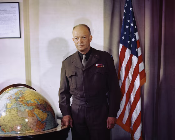 Portrait of Dwight Eisenhower standing between a large globe and an American flag