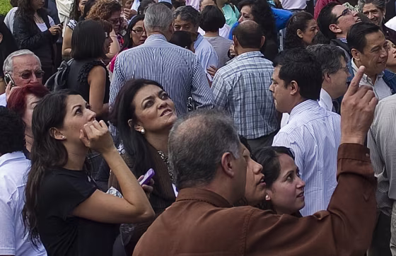 People stare at a building after rushing out onto the streets of the Roma neighborhood in Mexico City following a new quake.