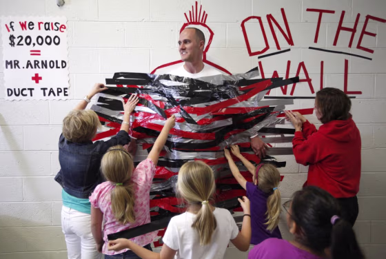 Ooltewah Elementary School students duct tape Principal Tom Arnold to a wall in the hallway during their lunch hour on April 27 in Ooltewah, Tenn. Arnold made an agreement with the students that if they reached their walk-a-thon fundraising goal of $20,000, he would spend the lunch hour duct taped to the wall.
