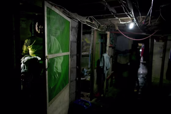 A man stands next to the door of his room under a bridge in Manila on August 21, 2012. Families cram into small rooms under a bridge so they can live for free.