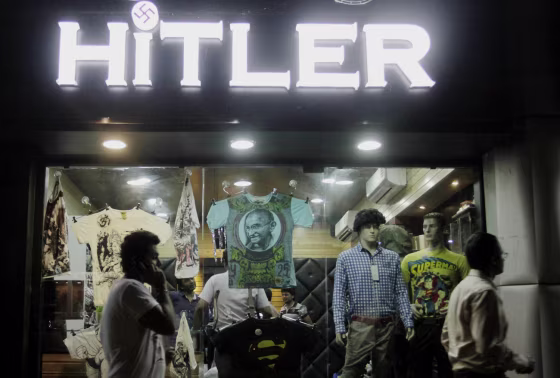 Indians walk past a shop named
