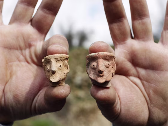 An employee of the Israeli Antiquities Authority displays figurines at Tel Motza archaeological site on the outskirts of Jerusalem.