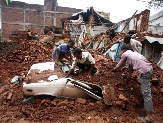 Municipal Corporation workers removes debris from a crushed car, after a three storyed building collapse during monsoon rain showers in Bhopal, Madhya Pradesh, India, on Tuesday. Reports state that several four and two wheeler vehicles were damaged and crushed under the debris and no casualties were reported in the incident.