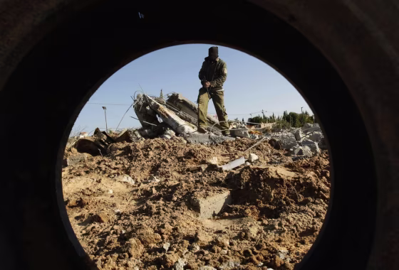 A masked Palestinian Islamic Jihad militant is seen through a tyre as he surveys the damage at a training camp after an Israeli air strike in Gaza December 29, 2011. The Israeli army confirmed that it targeted two sites in Gaza, including the training camp, and added that the strikes were carried out in response to the firing of rockets from Gaza into Israel on Wednesday. No injures were reported in Gaza. REUTERS/Ibraheem Abu Mustafa (GAZA - Tags: POLITICS CIVIL UNREST TPX IMAGES OF THE DAY)