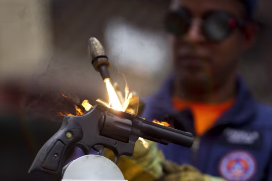 A worker destroys a weapon confiscated by the police during a news conference in Caracas.
