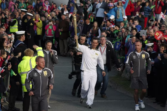 Triple Olympic gold medal-winning sailor Ben Ainslie carries the flame as the first torchbearer of the torch relay around Britain on Saturday.