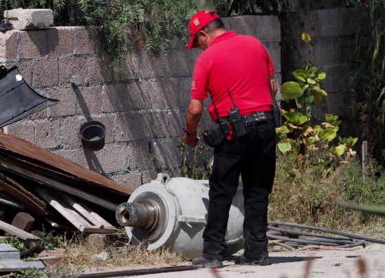 A firefighter takes photographs of the radiation head that was part of a radiation therapy machine, in the patio of the family who found the abandoned radiation head in a nearby field in the village of Hueypoxtla, Mexico, Dec. 5, 2013.
