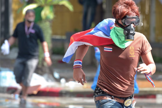 Thai anti-government protesters run from tear gas during a rally at a stadium to register party-list candidates in Bangkok on Thursday.