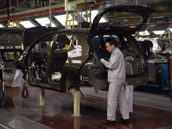 Photo taken on December 7, 2013 shows workers on the assemby line at the Sino-French joint venture Dongfeng Peugeot-Citroën Automobile (DPCA) plant in...