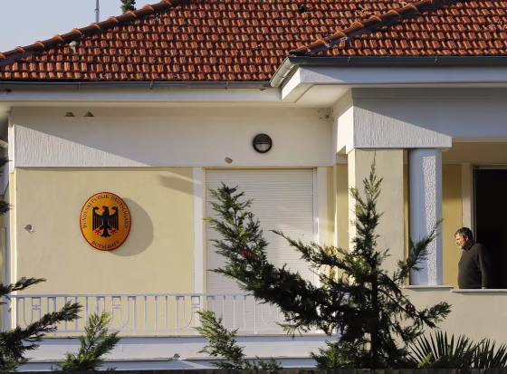 Bullet holes can be seen on the wall as German Ambassador in Greece, Wolfgang Dold, walks at his residence's balcony following an attack by unknown gunmen early Monday in an Athens suburb.