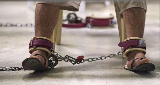 A detainee wears restraints as he reads during a class at Guantanamo Bay in March 2010.