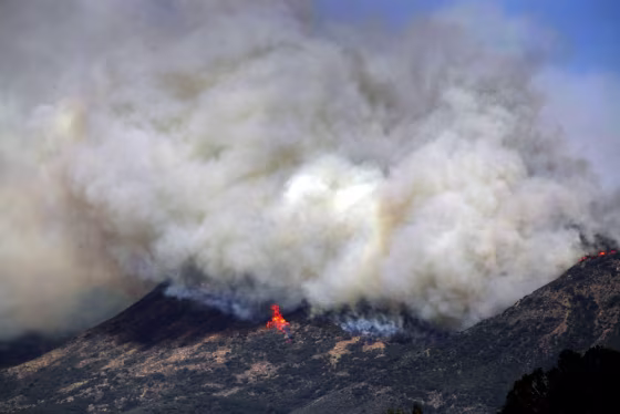 Smoke and fire billows over a hill near Thousand Oaks, Calif. on Thursday. Authorities have ordered evacuations of a neighborhood and a university about 50 miles west of Los Angeles where a wildfire is raging close to subdivisions. The blaze on the fringes of Camarillo and Thousand Oaks broke out Thursday morning and was quickly spread by gusty Santa Ana winds. Evacuation orders include California State University, Channel Islands.