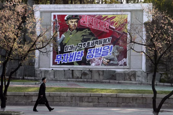 A man walks by a poster reading