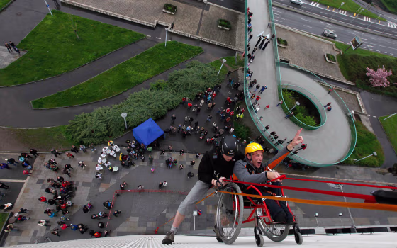 Jakub Koucky (R), a graduate from Jedlickuv Institute, is helped by a climber during the first ever attempt to rappel from Prague's Congress Center in a wheelchair, at an event to mark the institute's 100th founding anniversary in Prague, May 4, 2013. The institute was started by Rudolf Jedlicka a century ago to educate handicapped children. REUTERS/Petr Josek (CZECH REPUBLIC - Tags: ANNIVERSARY EDUCATION HEALTH SOCIETY TPX IMAGES OF THE DAY)