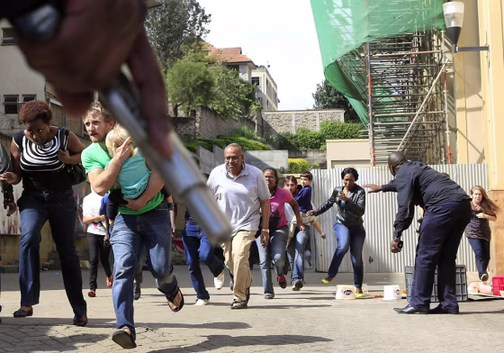 A police officer holds a gun to provide cover for customers running out as a shooting took place at the Westgate shopping mall in Nairobi on Sept. 21.