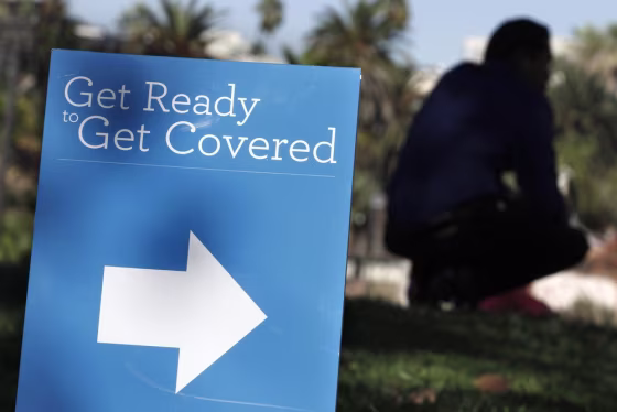 A man is silhouetted behind a sign at an Affordable Care Act outreach event hosted by Planned Parenthood for the Latino community in Los Angeles, Cali...