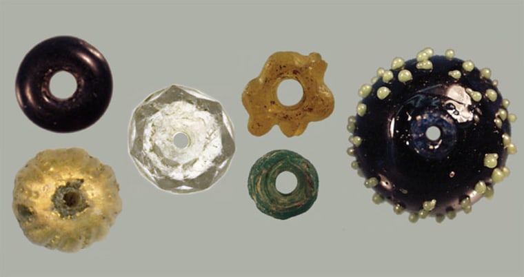 Beads from St. Catherines Island. From left to right: On top French manganese black opaque bead, some created with the a speo process; bottom Spanish spherical dot-incised gilded glass bead (6 found); cut crystal, potentially manufactured in Spain because of inferior quality to known beads from France or Venice (6 found, as well as other nonglass beads of carnelian, jet and amber); On top unique yellow melon shaped bead, possibly from China; bottom Chinese wound translucent-transparent green (4 found); blown black bead with greenish-yellow dots (13 found with one burial that are potentially French). Credit: AMNH