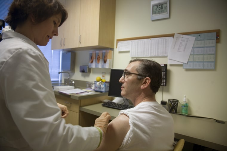 Pharmacist Meredith Potochnic, left, prepares to give Dr. Warren Dinges, 41, a shot of H1N1 vaccine in Seattle.