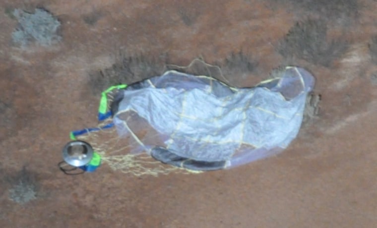 An aerial photograph shows the Hayabusa sample return capsule, seemingly intact, along with its parachute in the Australian Outback.