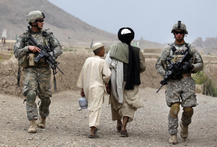 Image: Villagers pass US soldiers on patrol in Kandahar region