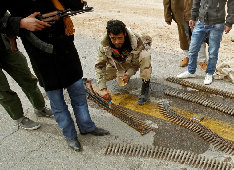 Image: A rebel fighter cleans the ammunition rounds of an anti-aircraft weapon in Ajdabiya