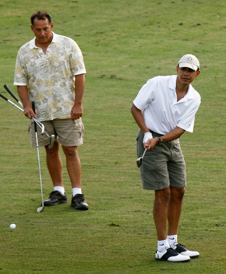 Image: President Barack Obama chips onto the ninth green as friend Robert Titcomb watches while playing golf at the Mid-Pacific Country Club in Kailua, Hawaii