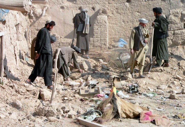 Image:  Afghan men examine a destroyed house