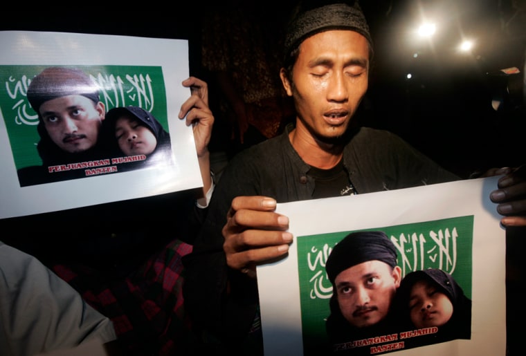 A supporter of Bali bomber Imam Samudra cries while carrying a picture of Samudra and his daughter during prayers in Serang
