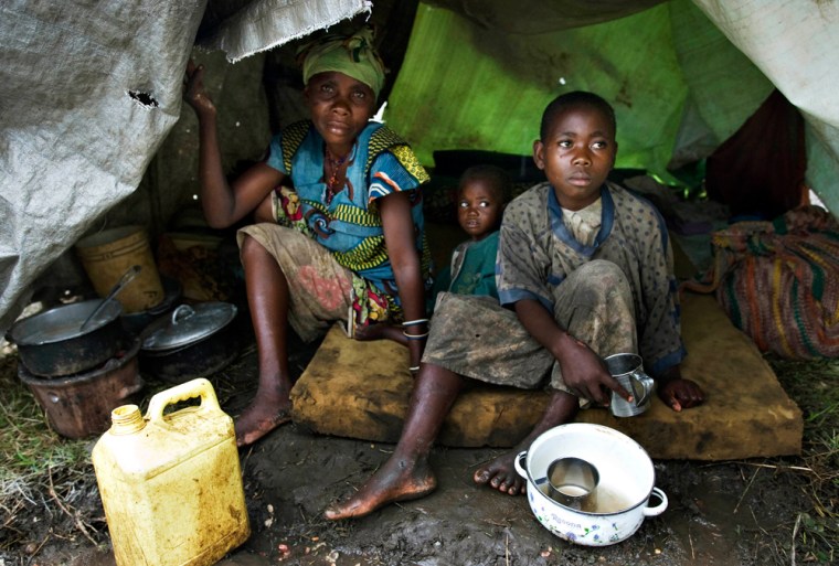 Family displaced by fighting takes shelter from the rain in a makeshift tent in Kiwanja