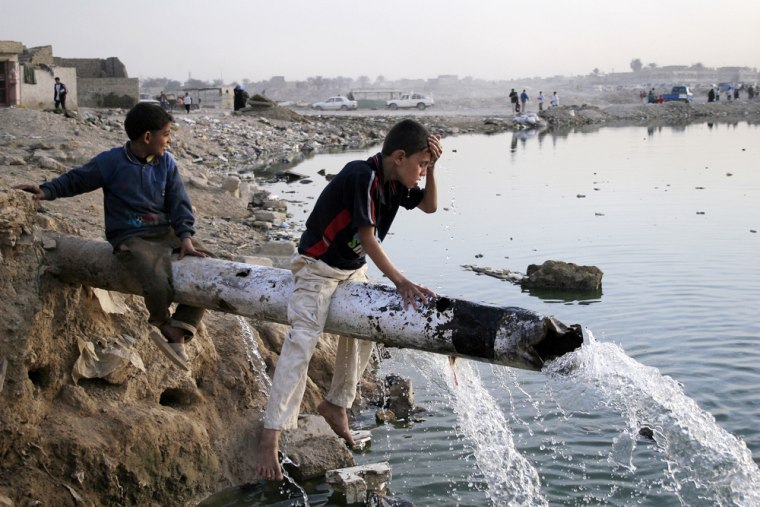 Image: Iraqi boy washing his face with water from a burst water pipe
